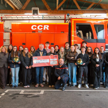 Étudiants avec un devant un camion de Pompier avec un immense chèque en carton