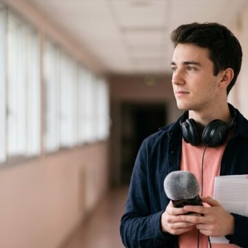 Alt : Portrait d'un étudiant en communication tenant un enregistreur audio dans un couloir lumineux